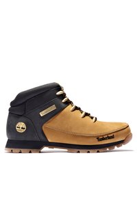 Timberland fottur for hiking med en overdel i lysbrun semsket skinn, svarte lærdetaljer, gullhardware, og en robust gummisåle med godt grep.