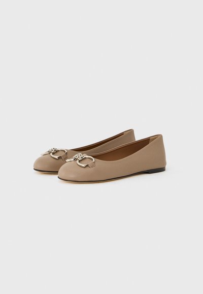 Ballerines en cuir beige avec un bout rond et un accent en métal argenté à l'avant. Semelle plate, texture lisse et design minimaliste.