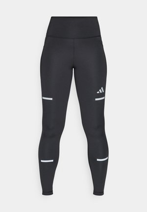 Black leggings with a high waistband, made from smooth material. Features white reflective stripes near the knees and an Adidas logo.
