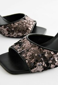 Sandales noires à bout ouvert avec une large bride en sequins présentant des nuances variées de rose et de noir. Semelle plate et texture lisse.