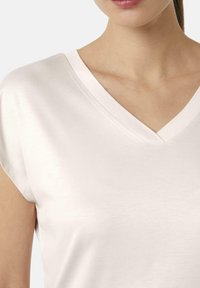 Lichtroze V-hals t-shirt met korte mouwen, gemaakt van een gladde stof, met een subtiele glans en zonder zichtbare patronen of versieringen.