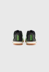 Schwarze und grüne Sportschuhe mit Netzpaneelen. Mit "JAKO"-Markenlogo in Grün auf der Ferse. Gummisohle, kontrastierende Texturen.