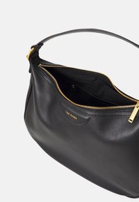 Sac à épaule en cuir noir avec quincaillerie dorée, doté d'une fermeture éclair, d'une surface lisse et d'une poche intérieure. Logo embossé à l'avant.