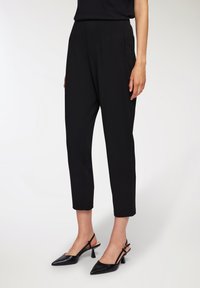 Czarne dopasowane spodnie o prostym kroju, z bocznymi kieszeniami i gładką fakturą. Zestawione z czarnymi szpilkami typu slingback o spiczastym nosku.