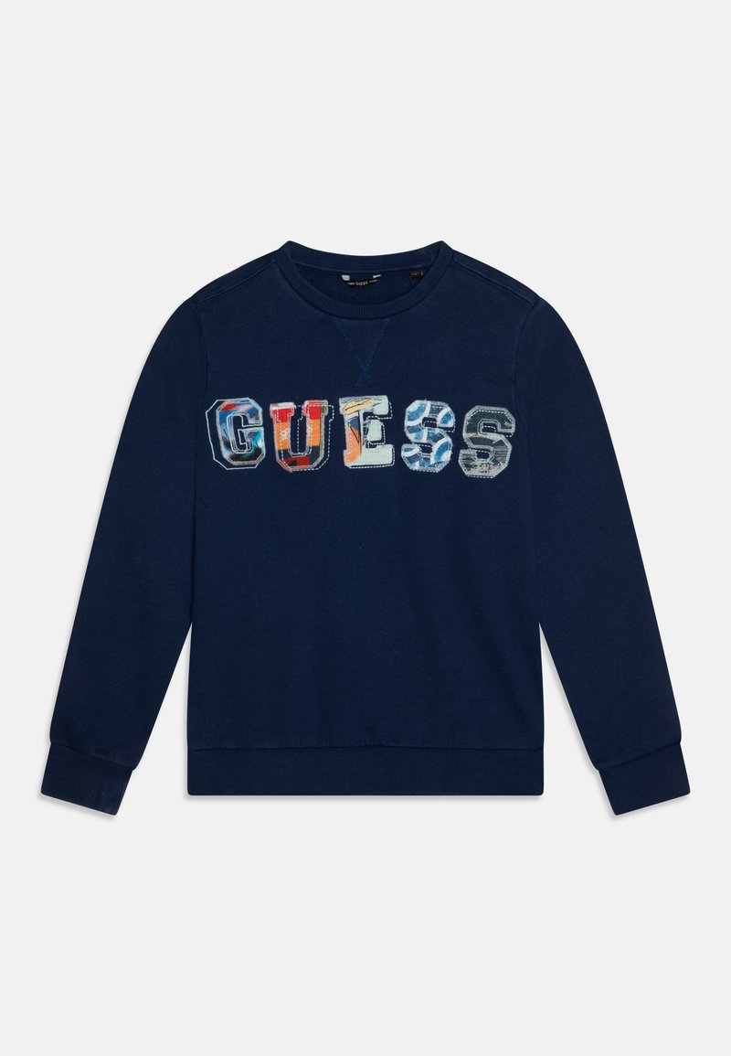 Sweat-shirt bleu marine à manches longues avec des lettres en patchwork colorées formant le mot « GUESS » sur la poitrine.