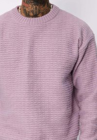 Pull en laine rose texturé avec un col rond, des poignets côtelés et une coupe ample. Présente un motif tissé et un tissu doux.