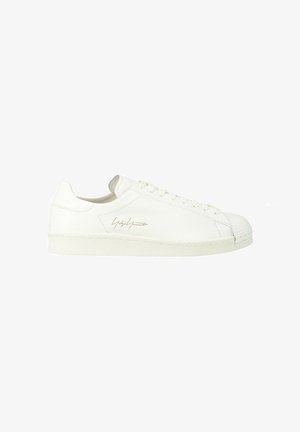 Sneaker bianca low-top con lacci e logo firma dorato sul lato, suola piatta e finitura in pelle liscia.