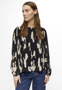 Blusa de manga larga en azul marino con un patrón abstracto en crema, que presenta mangas abullonadas y un dobladillo recto, fabricada en una tela ligera.