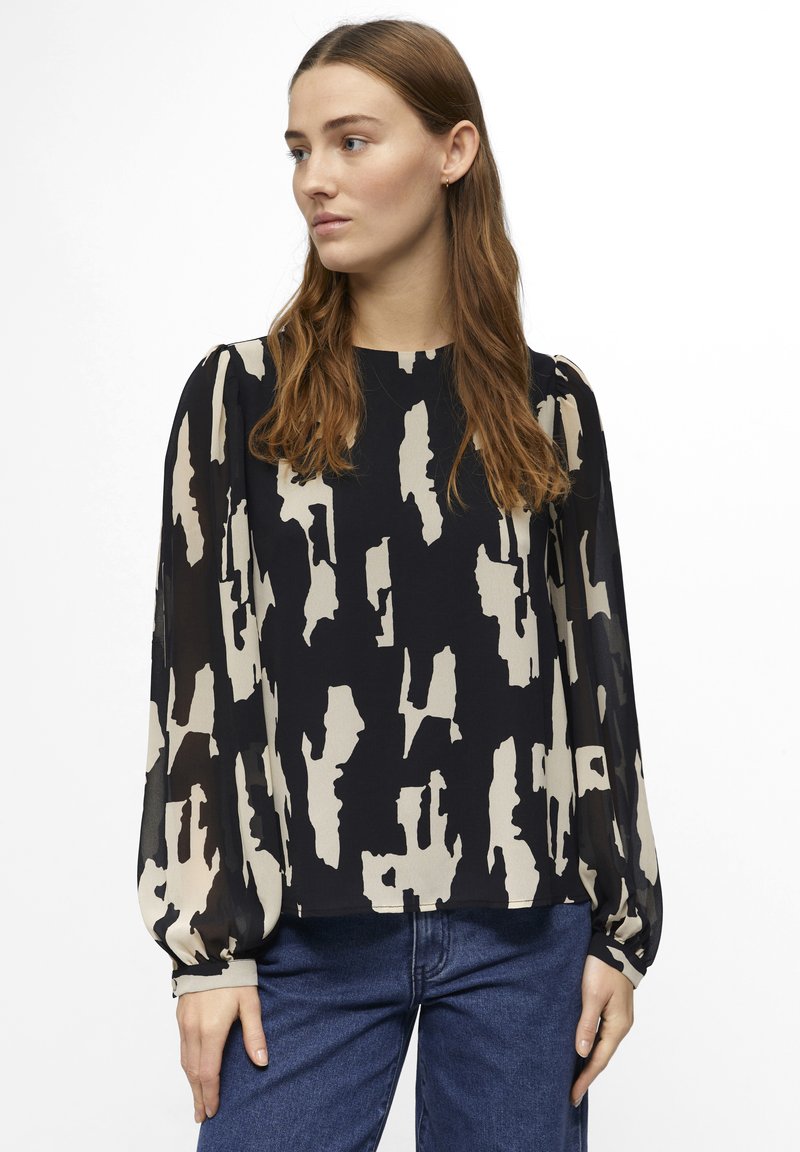 Blusa de manga larga en azul marino con un patrón abstracto en crema, que presenta mangas abullonadas y un dobladillo recto, fabricada en una tela ligera.