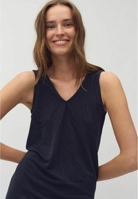 Top fără mâneci, de culoare bleumarin, cu decolteu în V, realizat dintr-un material moale și cu o croială lejeră, având un design minimalist și o textură netedă.