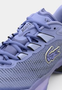 Chaussure de sport violette avec dessus en maille, tissu texturé, accents argentés et logo. Comprend un système de laçage flexible et un talon structuré.
