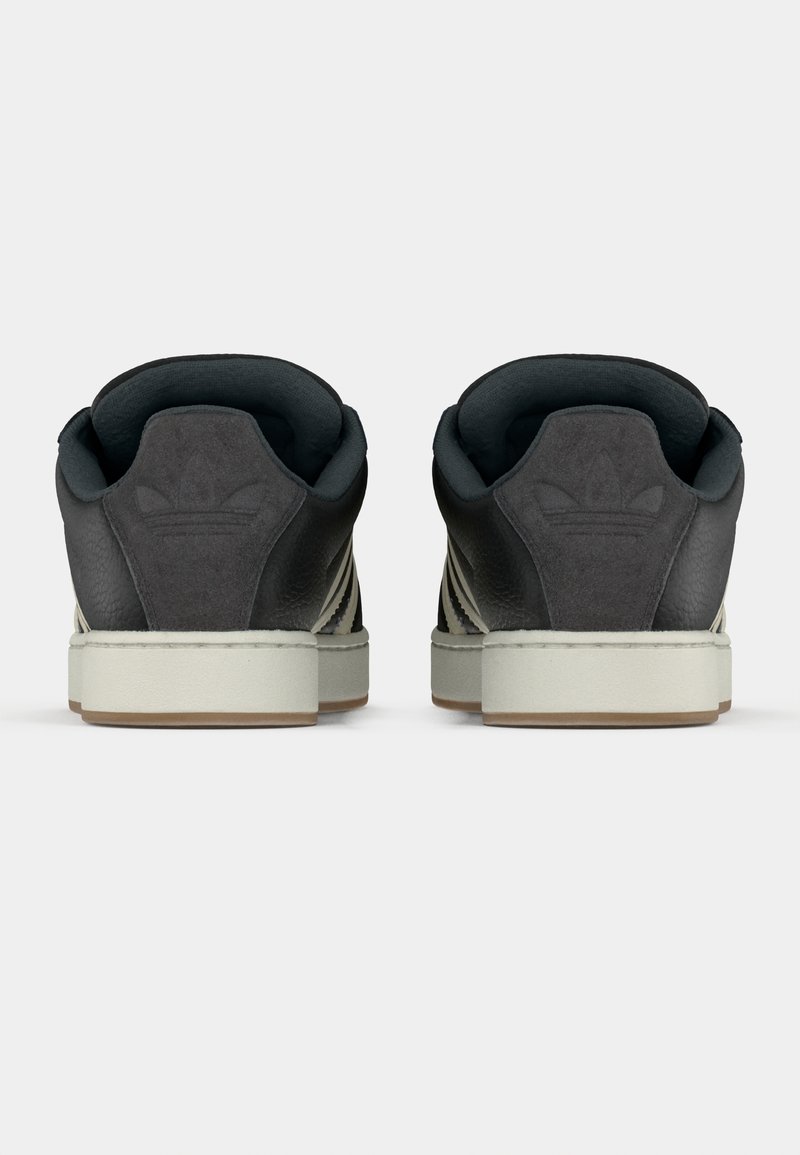 Paar schwarze Adidas-Sneaker von hinten gesehen, mit grauen Wildleder-Fersenpatches und eingeprägtem Logo sowie weißen Mittelsohlen.