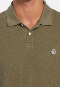 Olivově zelená polo košile z texturované látky, s klasickým límečkem, tříknoflíkovým zapínáním a malým logem tučňáka na prsou.