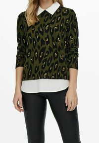 Maglione verde oliva con stampa leopardata nera e beige, maniche lunghe e una camicia bianca sottostante, abbinato a pantaloni neri.