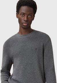 Szary sweter w prążki z okrągłym dekoltem i długimi rękawami, wykonany z teksturowanej tkaniny z małym logo na piersi.