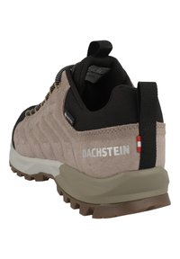 Vaelluskengät, joissa on beige ja musta väritys, teksturoitu mokkanahkapintainen päällinen, vahvistettu kanta, harmaa kumipohja ja heijastava logoyksityiskohta.