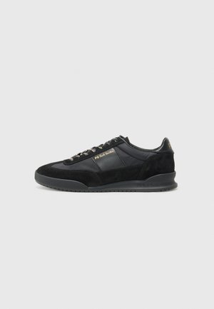 Black athletic sneakers featuring a combination of smooth leather and suede, round toe, textured sides, and gold branding accents.