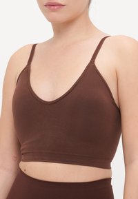 Bralette marrone senza cuciture con scollatura a V, spalline regolabili e design corto. Texture morbida che mette in risalto il décolleté con un leggero supporto.