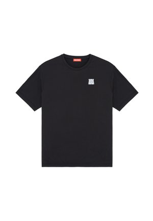 T-shirt noir à manches courtes avec un petit logo géométrique blanc sur la poitrine gauche et une étiquette rouge à l'intérieur du col.