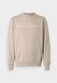 Sudadera beige con cuello redondo, mangas largas y texto blanco "TOMMY HILFIGER EST. 1985" impreso en el frente. Puños y dobladillo acanalados.
