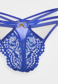 Niebieska koronka bielizny z misternymi kwiatowymi wzorami, przezroczystymi panelami, regulowanymi ramiączkami oraz złotymi ozdobami w centrum.