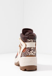 Wysokie sneakersy z brązowym, kremowym i pomarańczowym wzorem w wężową skórę, gruba biała podeszwa oraz branding "Michael Kors" na pięcie.