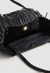 Bolso de cuero negro con detalles de flecos, cierre magnético y bolsillo interior con cremallera de textura suave. Acentuado con herrajes dorados.