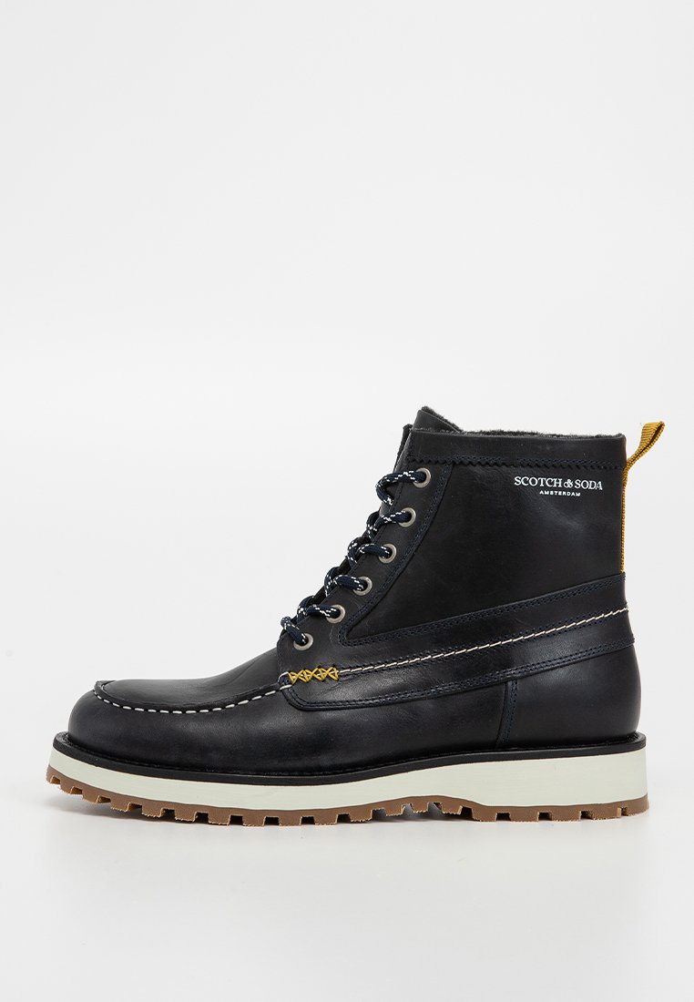 Botte en cuir noir avec des coutures blanches, des accents dorés, un design à lacets et une semelle en caoutchouc texturé ; dotée d'une poignée jaune à l'arrière.
