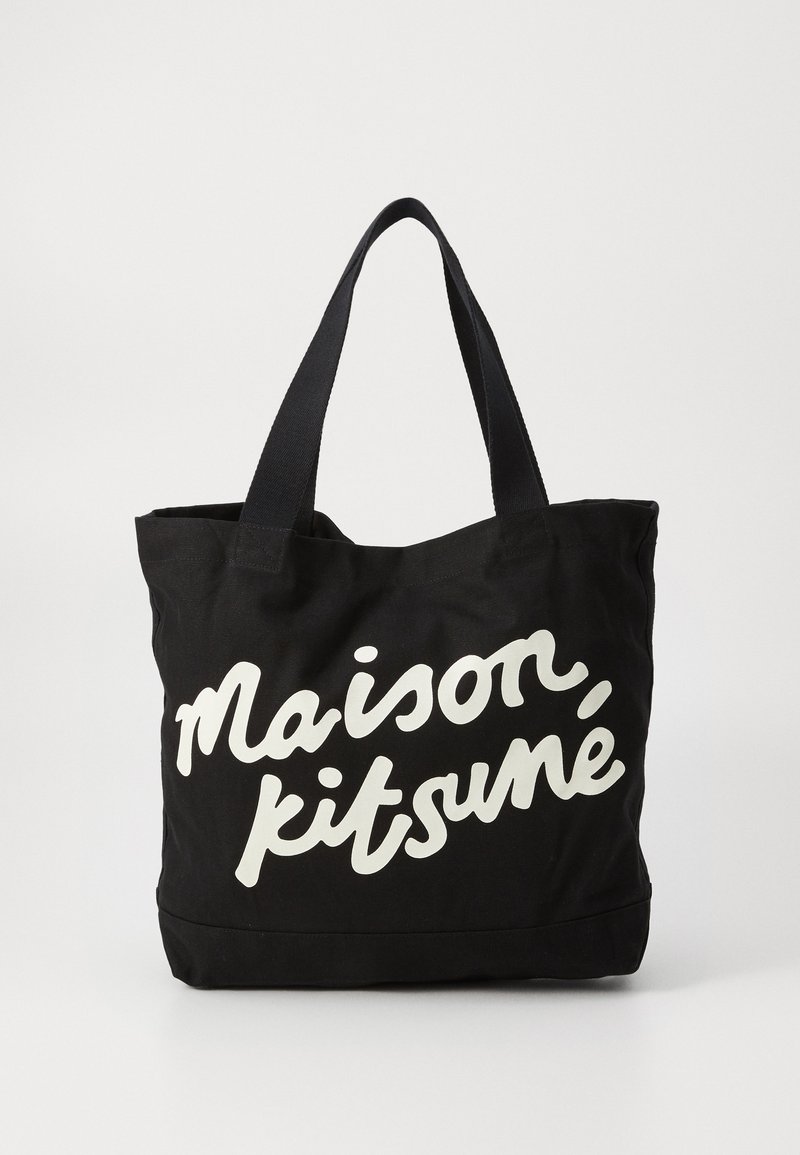 Saco tote de tela preta com texto em letras cursivas brancas "Maison Kitsuné" na parte da frente. Apresenta alças de tecido preto resistentes e combinantes.