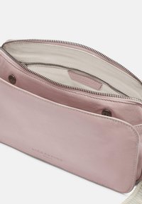 Pink leather bag with a zip closure, featuring a textured surface and a lined interior. Includes a visible brand label inside.