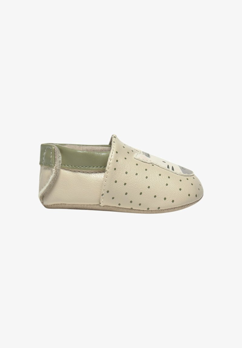 Zapato de cuero tipo mocasín en color beige con detalles verdes, presenta un patrón de puntos y un diseño de punta redondeada para facilitar su uso.