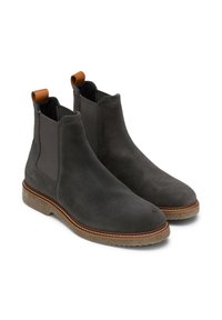 Grijze suède Chelsea boots met elastische zijpanelen, bruine leren trekbanden en lichtbruine rubberen zolen. Decoratieve stiksels langs de rand van de zool.