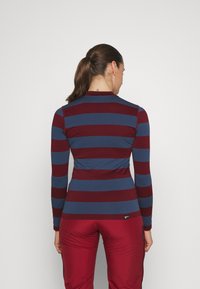 Langermet topp med veksling mellom maroon og blå horisontale striper, laget av et mykt stoff, med en tettsittende design og rund hals.