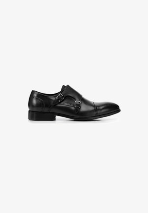 Zapato de vestir de cuero negro con un diseño elegante, punta afilada, acentos de doble hebilla y un tacón bajo cuadrado. Textura suave con detalles de costura.