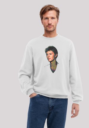 Weißes Sweatshirt mit einem farbigen Porträt-Druck. Der Stoff ist weich, mit einem Rundhalsausschnitt und gerippten Bündchen. Getragen mit blauen Jeans.
