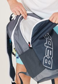 Mochila con un exterior gris oscuro, que presenta una gran apertura con cremallera, un bolsillo lateral de malla y tiradores de cremallera coloridos para un acceso fácil.