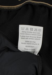 Zwarte stoffen shorts met een zachte textuur, voorzien van een interne verzorgingslabel en gouden stiksels. Inclusief verzorgingsinstructies en productdetails.