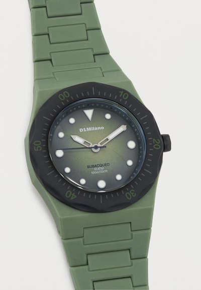 Ρολόι με πράσινο λουράκι σιλικόνης, μαύρο στεφάνι, στρογγυλό καντράν, λευκούς δείκτες ώρας και το όνομα της μάρκας D1Milano, που υποδεικνύει αντοχή στο νερό έως 10 ATM.