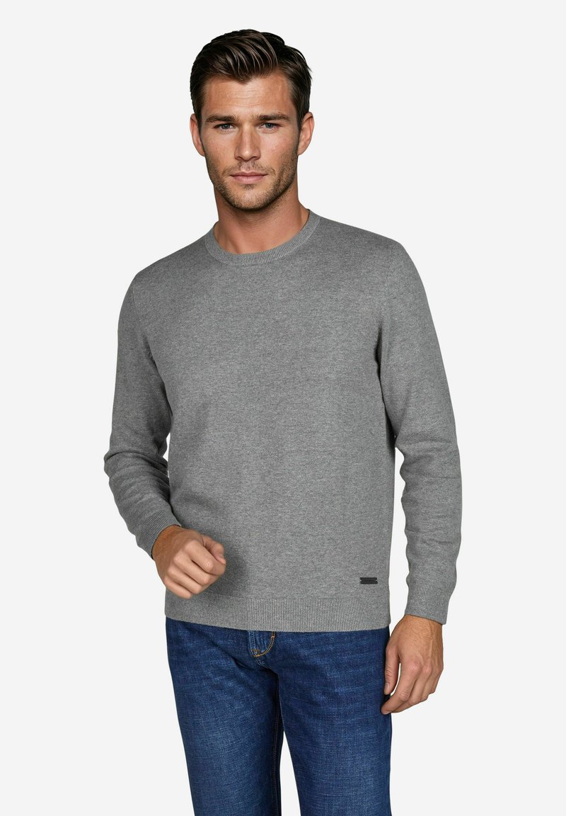 Grau gestrickter Pullover mit Rundhalsausschnitt und gerippten Bündchen, kombiniert mit dunkelblauen Jeans. Verfügt über ein kleines schwarzes Markenschild am Saum.