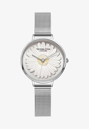 Montre-bracelet avec un bracelet en maille argentée, un motif de marguerite blanche sur le cadran et des aiguilles argentées indiquant l'heure.