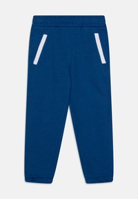 Mėlynos sportinės kelnės, turinčios elastinį juosmens diržą, dvi baltas šonines kišenes ir elastines rankoves prie kulkšnų. Pagamintos iš minkštos, kvėpuojančios medžiagos.