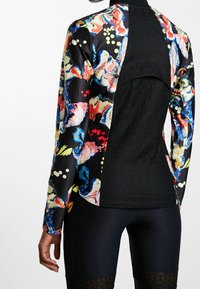 Długi rękaw z żywym kwiatowym wzorem na satynowej tkaninie, z jednolitym czarnym tyłem i fakturowanym wzorem, dopasowany krój.