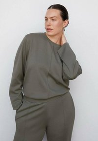 Olijfgroene, gestructureerde, lange mouwen top met een ronde hals, gecombineerd met bijpassende hoge taille broek; minimalistisch ontwerp en relaxte pasvorm.