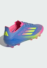 Blue and pink soccer cleat with a textured upper, neon accents, and a molded outsole featuring translucent pink studs.
