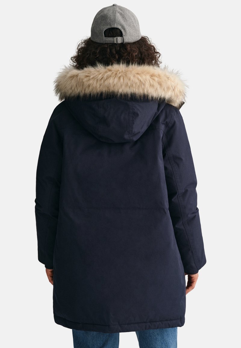 Marineblaue Parkajacke mit einer Kapuze aus Kunstfell, langen Ärmeln und geradem Schnitt. Sie zeichnet sich durch eine glatte Textur und ein praktisches Design aus.