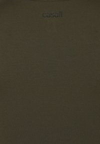 Ciemnooliwkowa sportowa koszulka wykonana z gładkiej, rozciągliwej tkaniny, z subtelną prążkowaną fakturą i czarnym logo "casall" z tyłu.