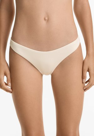 Seno bikini in un morbido tessuto beige chiaro a coste. Presenta un design a vita bassa con cinturini laterali sottili e una texture liscia.