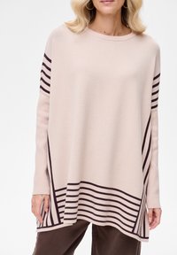 Lichtbeige trui met donkerbruine diagonale strepen aan de zoom en mouwen. Zachte textuur, ronde hals en een casual pasvorm.