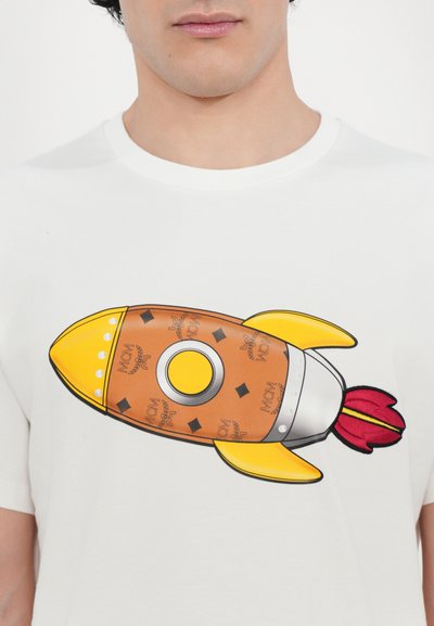 White T-shirt featuring a colorful rocket design. The rocket is orange with yellow accents, and it has a silver body and red flames.