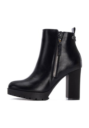 Botas de tobillo de cuero negro con un tacón alto y grueso, cremallera lateral y suela texturizada, con un acabado suave y mínimos acentos de herrajes.